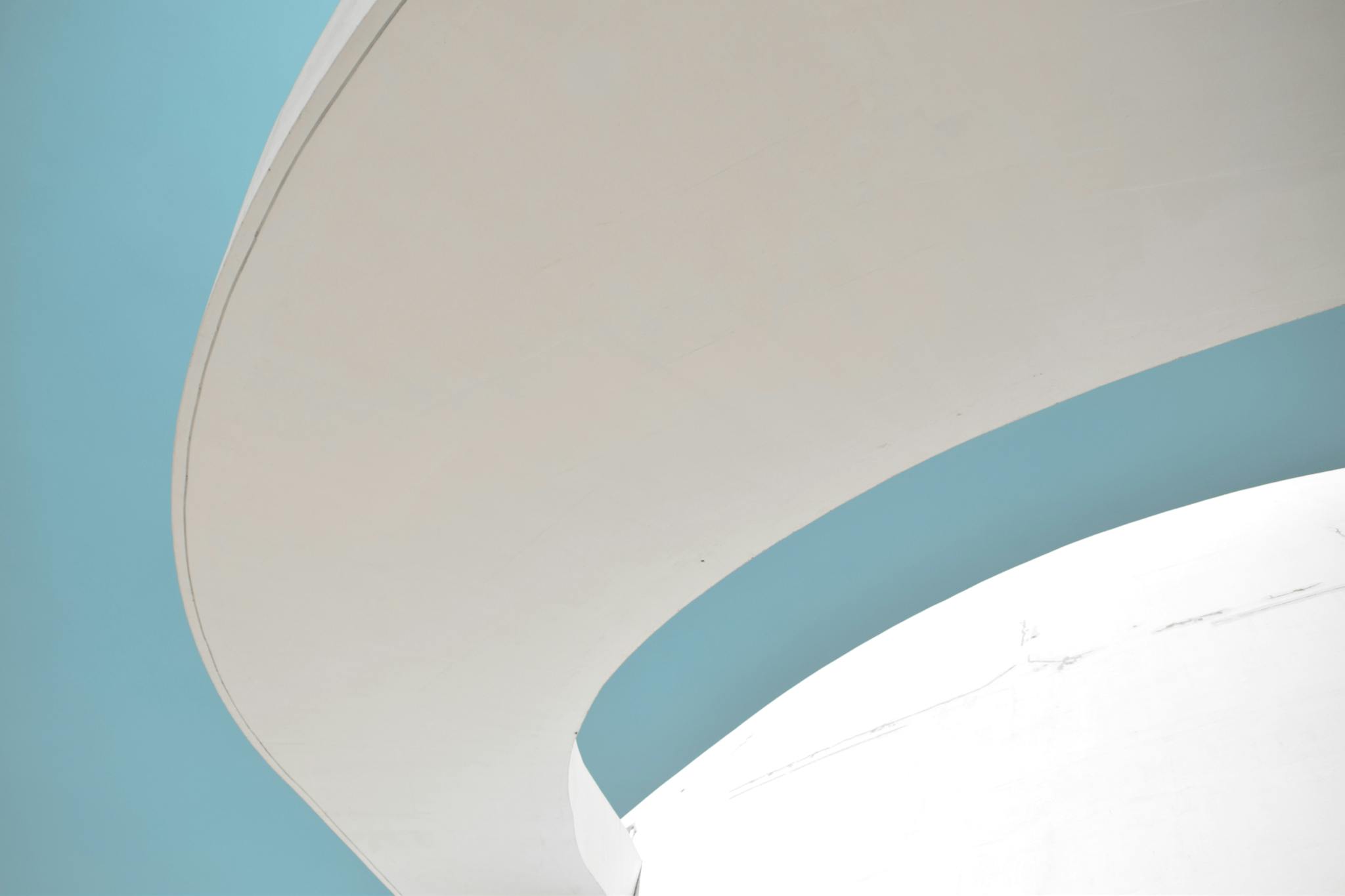 Abstract architectural detail featuring curves against a blue sky.