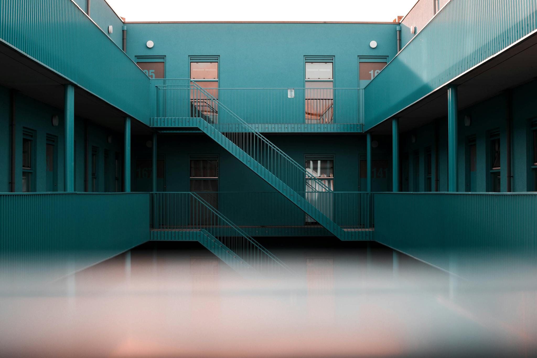 Modern interior view of a blue apartment complex featuring staircases and doors.